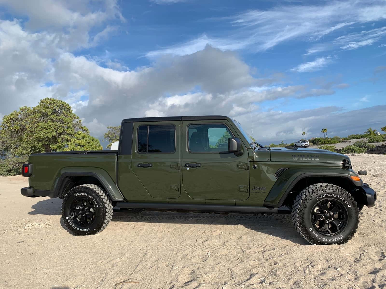 Army green Jeep Gladiator pickup on white sand